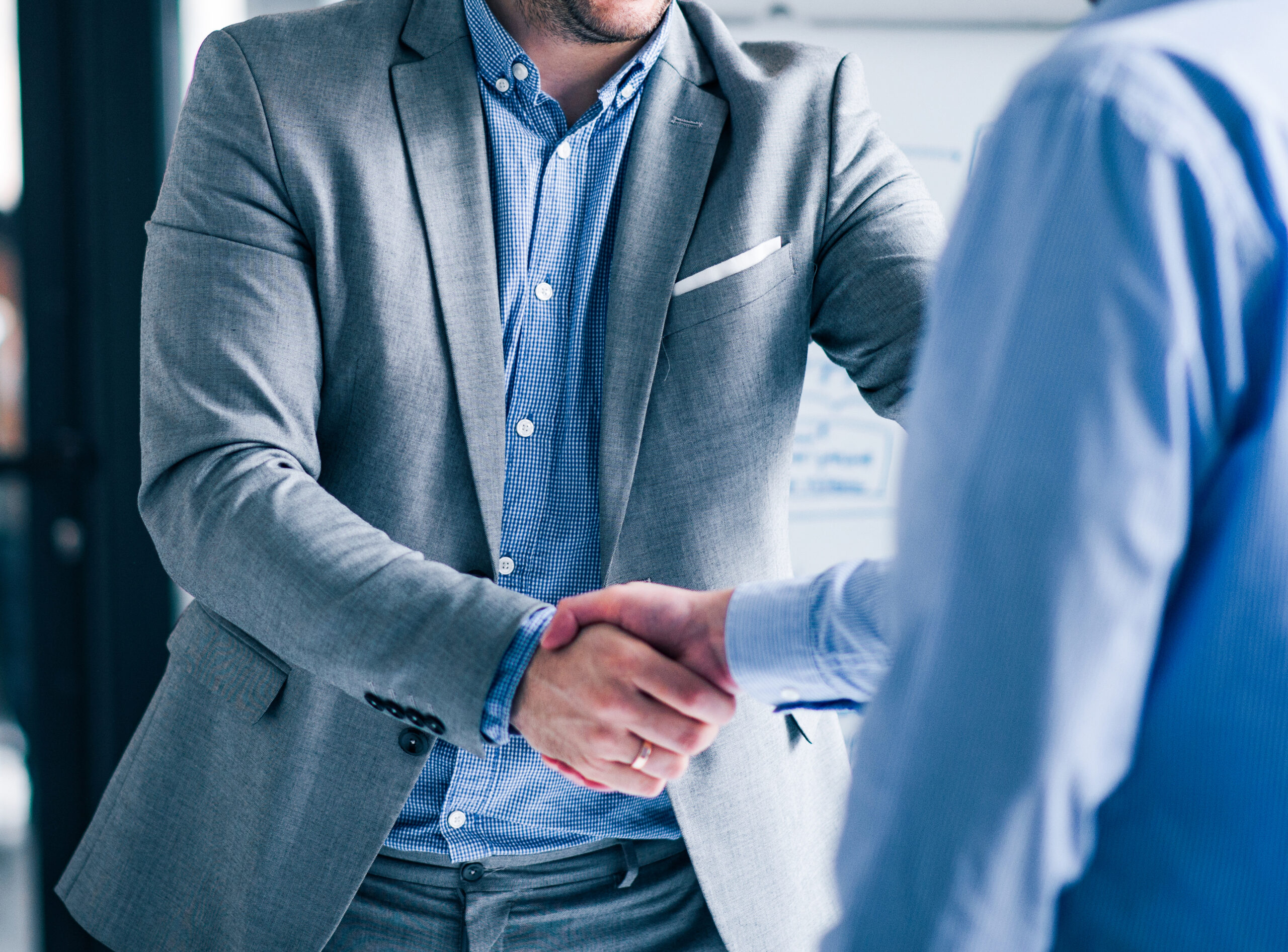 Two smiling businessmen shaking hands while standing in an offic Two smiling businessmen shaking hands while standing in an office.